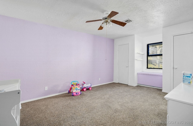 game room featuring a ceiling fan, visible vents, a textured ceiling, and carpet flooring