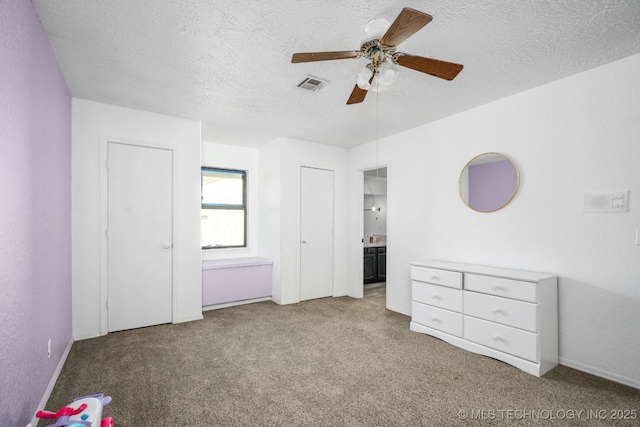 unfurnished bedroom featuring light carpet, a textured ceiling, connected bathroom, and visible vents