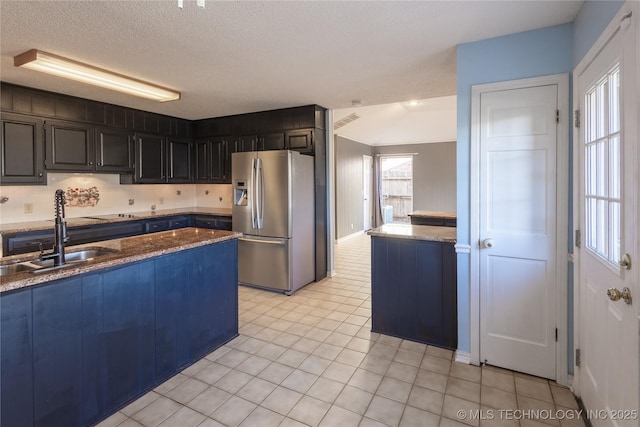 kitchen featuring sink, stainless steel refrigerator with ice dispenser, decorative backsplash, a textured ceiling, and light tile patterned flooring