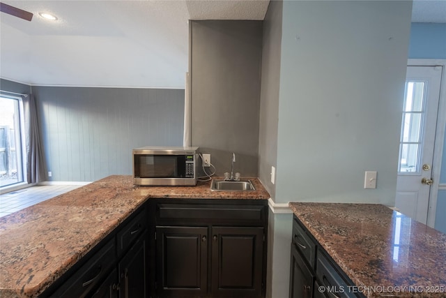 kitchen featuring kitchen peninsula, sink, and dark stone counters