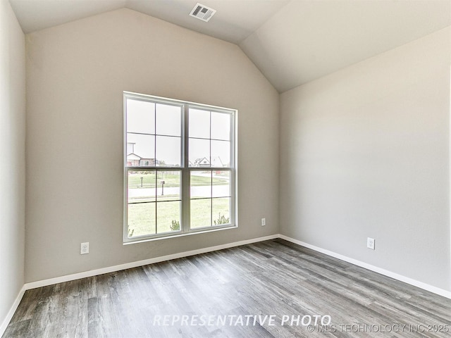 spare room with hardwood / wood-style flooring and lofted ceiling