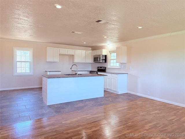 kitchen featuring stainless steel appliances, dark wood-type flooring, sink, white cabinets, and an island with sink