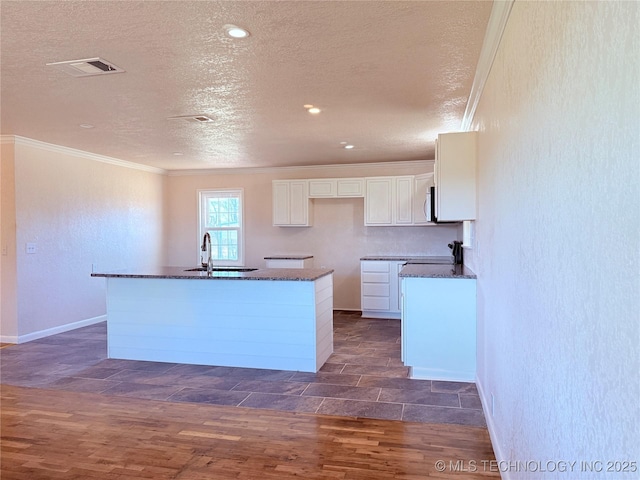 kitchen featuring white cabinetry, sink, an island with sink, and dark hardwood / wood-style floors