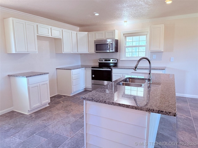 kitchen featuring sink, an island with sink, dark stone counters, white cabinets, and appliances with stainless steel finishes