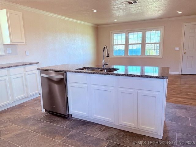 kitchen featuring white cabinets, a center island with sink, sink, and dark stone counters