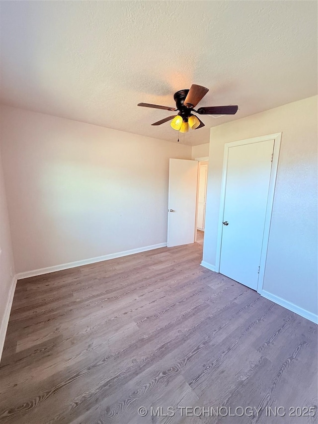 unfurnished bedroom featuring ceiling fan, wood-type flooring, and a textured ceiling