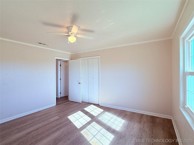 unfurnished bedroom featuring multiple windows, light wood-type flooring, a closet, and ceiling fan