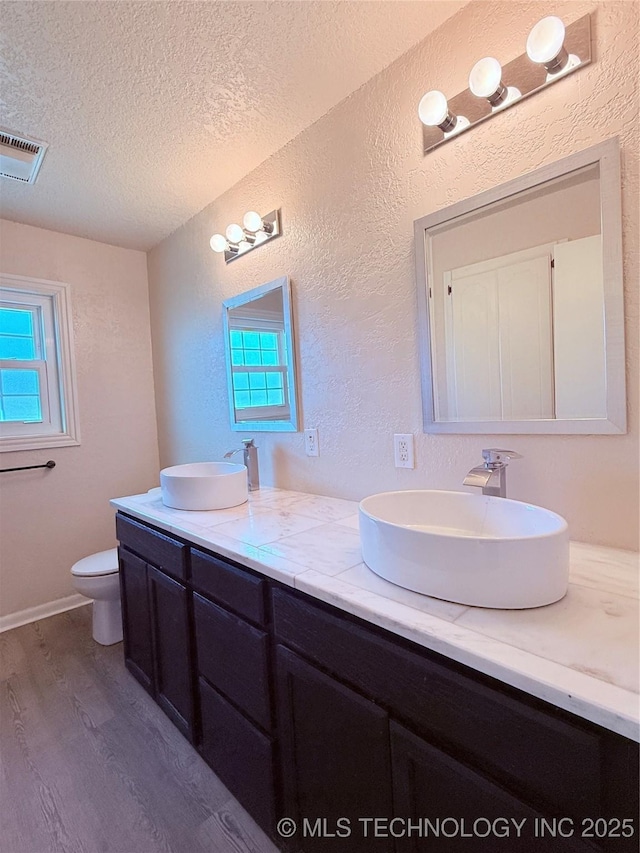 bathroom featuring hardwood / wood-style floors, toilet, a textured ceiling, and a wealth of natural light