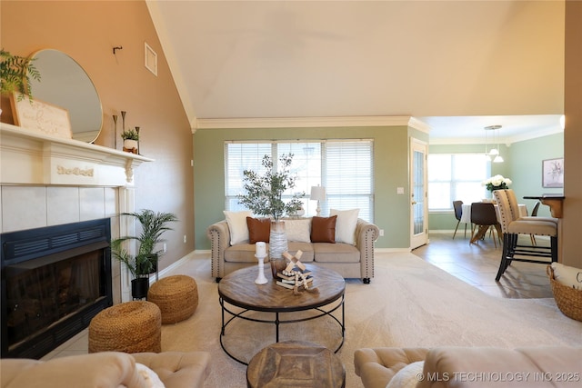 living room featuring crown molding, light colored carpet, a fireplace, and vaulted ceiling