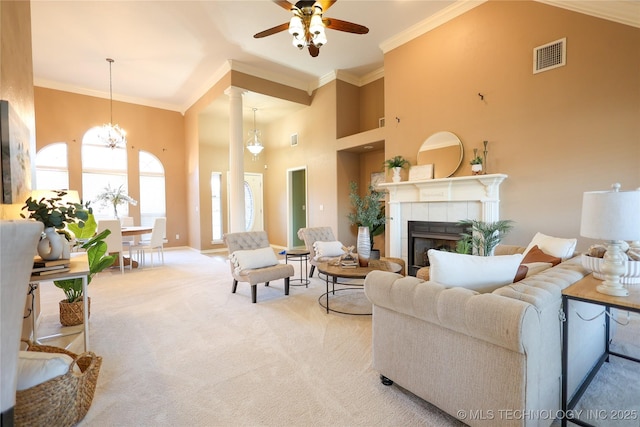 carpeted living room with a fireplace, a high ceiling, ceiling fan with notable chandelier, and crown molding