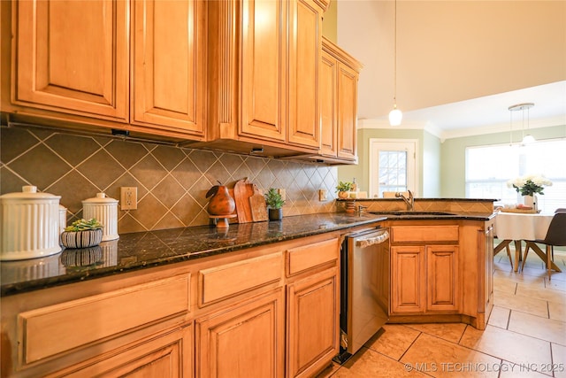 kitchen with dishwasher, dark stone counters, sink, light tile patterned floors, and decorative light fixtures