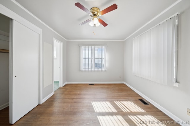 unfurnished bedroom with hardwood / wood-style floors, ceiling fan, ornamental molding, and a closet