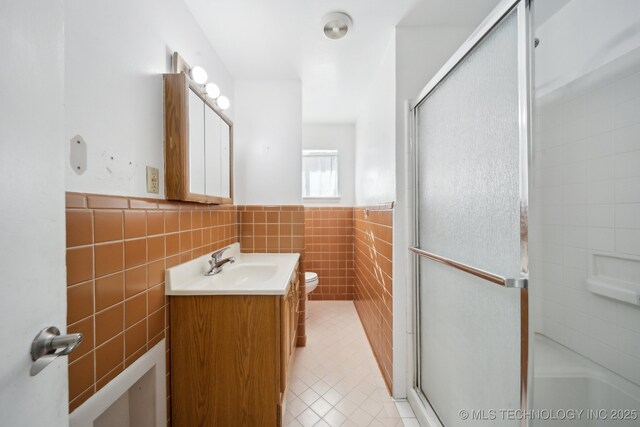 bathroom with vanity, tile patterned floors, toilet, tile walls, and walk in shower