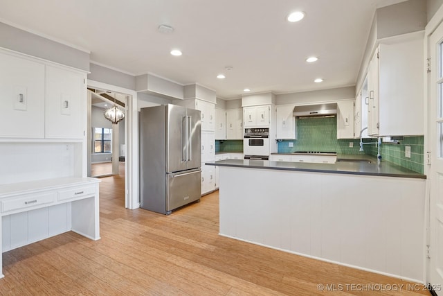 kitchen featuring white cabinets, sink, light wood-type flooring, range hood, and appliances with stainless steel finishes