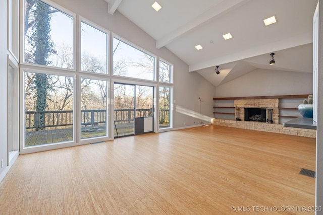 unfurnished living room with a stone fireplace, plenty of natural light, and high vaulted ceiling