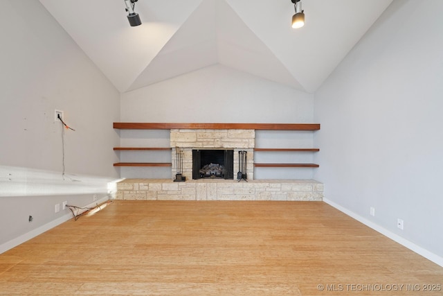 unfurnished living room with a stone fireplace, wood-type flooring, and lofted ceiling