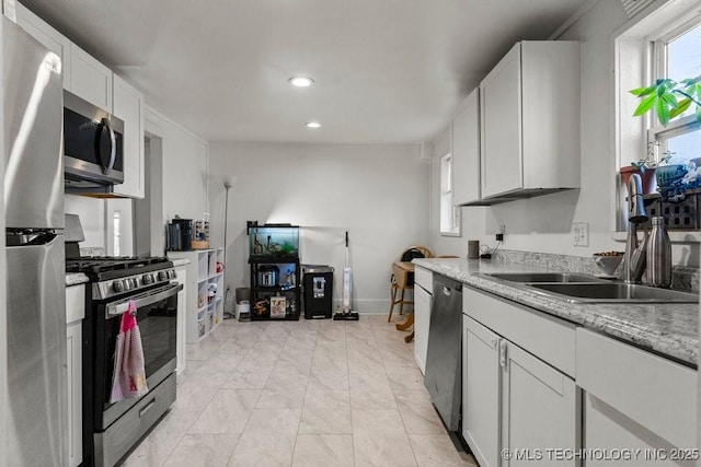 kitchen featuring light stone counters, sink, white cabinetry, and stainless steel appliances