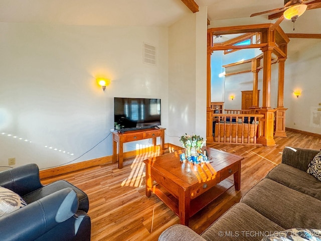 living room with ceiling fan, lofted ceiling with beams, and light wood-type flooring