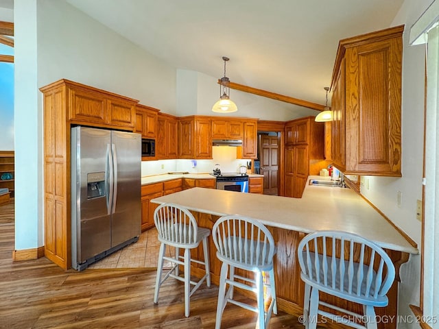 kitchen featuring appliances with stainless steel finishes, a breakfast bar, lofted ceiling, sink, and kitchen peninsula