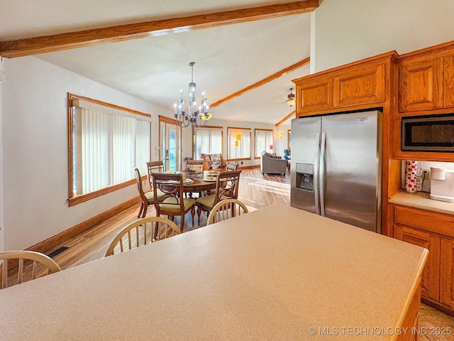 kitchen with light hardwood / wood-style flooring, appliances with stainless steel finishes, vaulted ceiling with beams, hanging light fixtures, and ceiling fan with notable chandelier