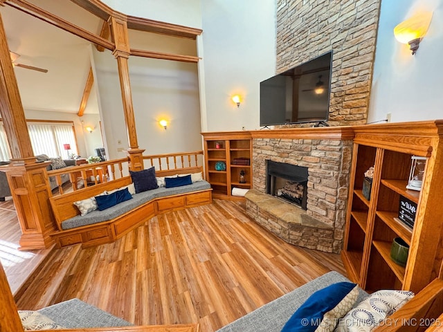 living room with a stone fireplace, ornate columns, high vaulted ceiling, hardwood / wood-style flooring, and ceiling fan