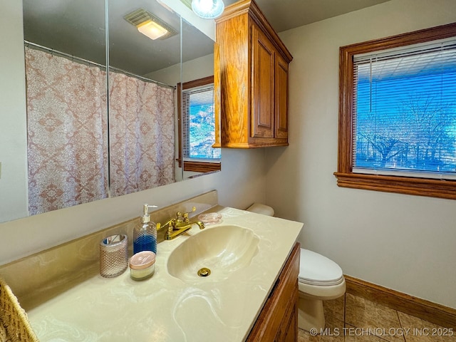 bathroom featuring vanity, a healthy amount of sunlight, tile patterned floors, and toilet