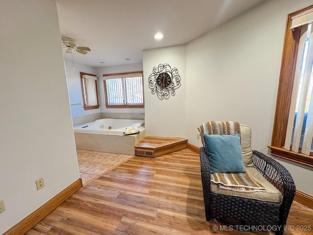 bathroom featuring a bath, hardwood / wood-style flooring, and ceiling fan