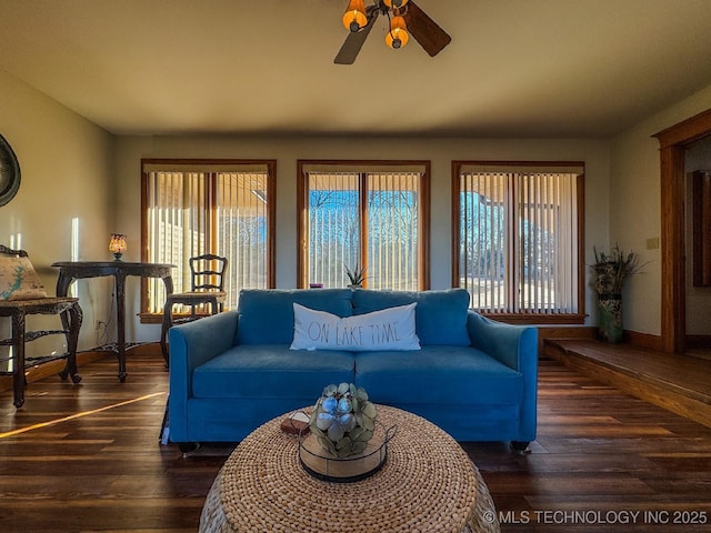 living room with a wealth of natural light, dark wood-type flooring, and ceiling fan