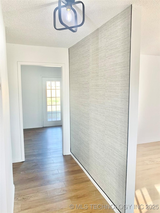 corridor with wood-type flooring and a textured ceiling