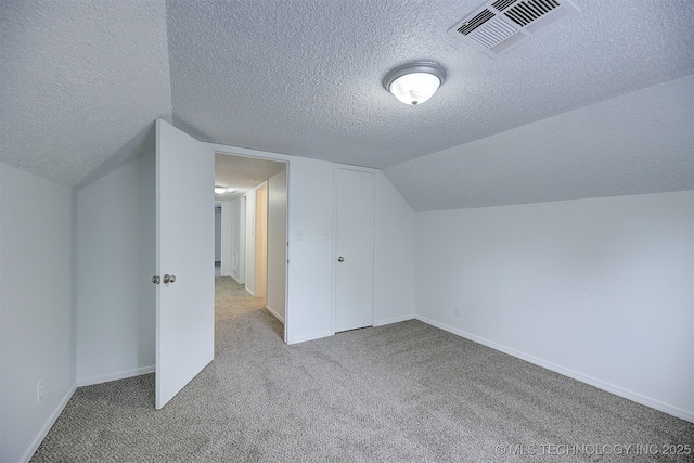 additional living space with light carpet, a textured ceiling, and vaulted ceiling