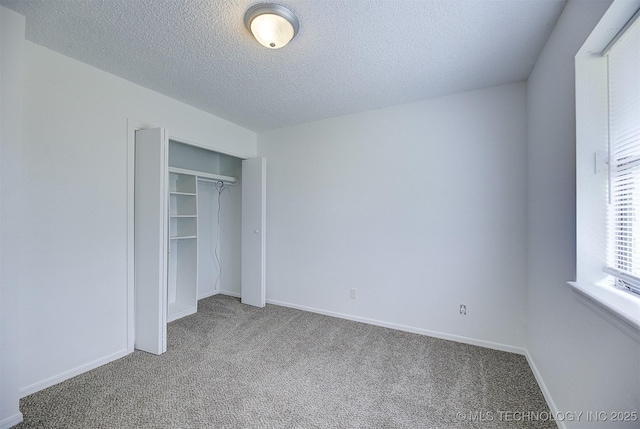 unfurnished bedroom featuring carpet floors, a textured ceiling, and a closet