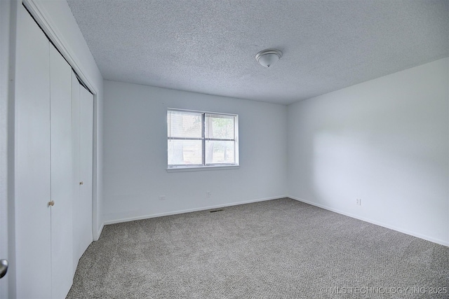 unfurnished bedroom with carpet flooring, a textured ceiling, and a closet