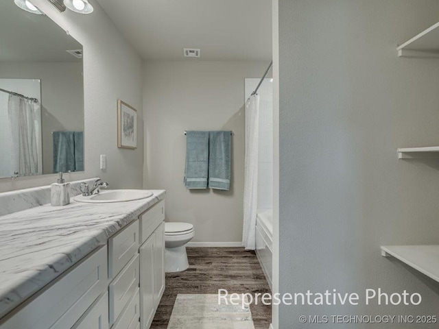 full bathroom with hardwood / wood-style flooring, vanity, shower / tub combo, and toilet