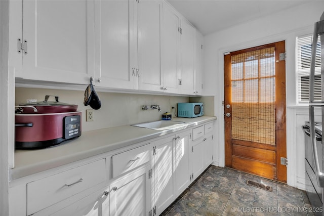 kitchen with white cabinets, range, and sink