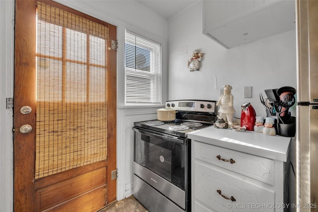 kitchen featuring light tile patterned floors, white cabinetry, and electric stove