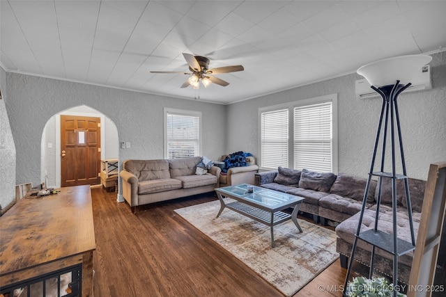 living room featuring a wall mounted AC, dark hardwood / wood-style flooring, ceiling fan, and ornamental molding