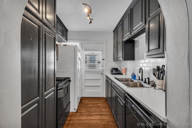 kitchen featuring sink, dark hardwood / wood-style floors, backsplash, track lighting, and black appliances