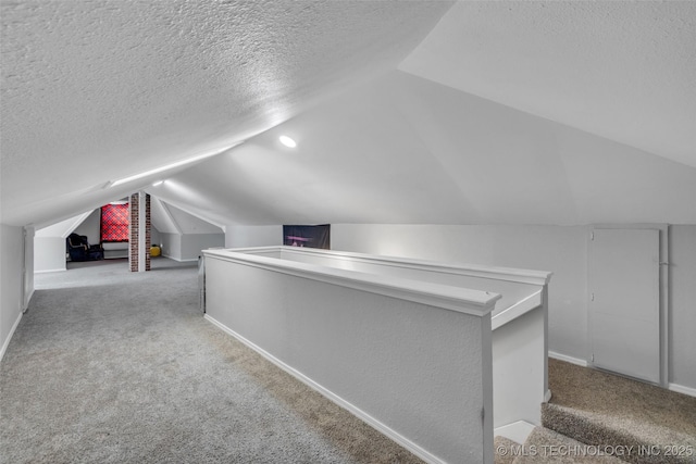 additional living space with vaulted ceiling, light colored carpet, and a textured ceiling