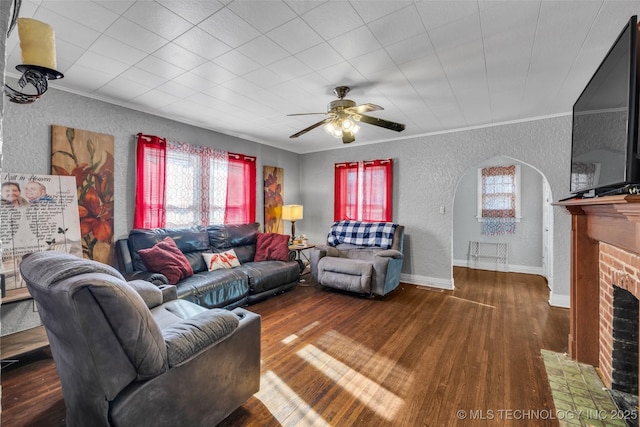 living room with a fireplace, dark hardwood / wood-style floors, ceiling fan, and ornamental molding