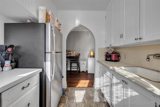 kitchen featuring white cabinets, stainless steel fridge, and sink