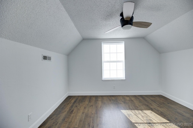 additional living space featuring dark hardwood / wood-style floors, ceiling fan, lofted ceiling, and a textured ceiling