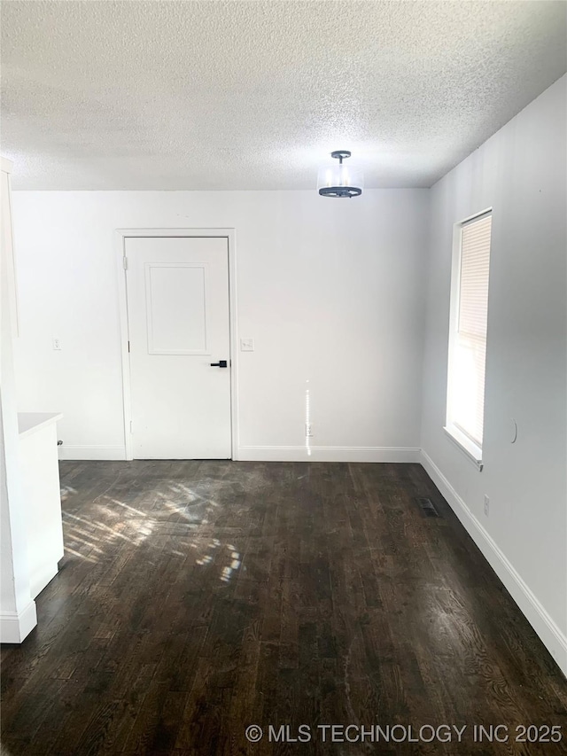 unfurnished room with a textured ceiling and dark wood-type flooring