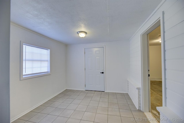 unfurnished room featuring crown molding, light tile patterned floors, and a textured ceiling