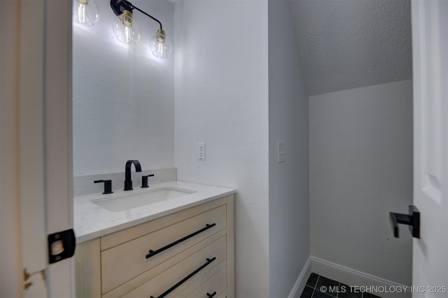 bathroom featuring tile patterned flooring, a textured ceiling, vanity, and vaulted ceiling