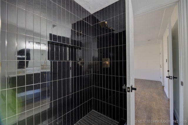 bathroom with a tile shower and hardwood / wood-style floors