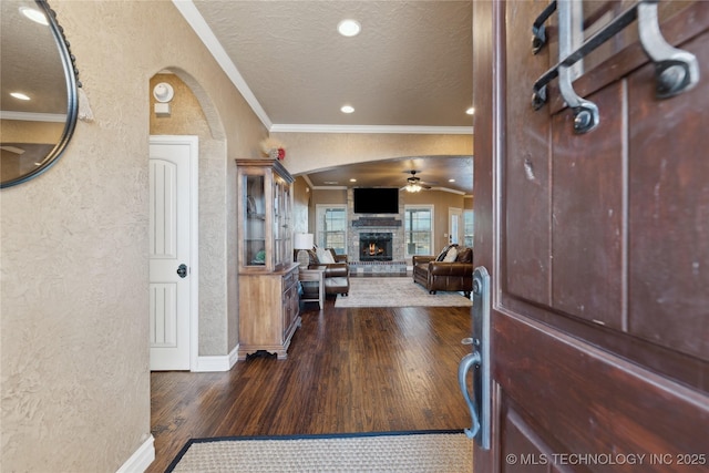 entryway with dark hardwood / wood-style flooring, ornamental molding, a textured ceiling, ceiling fan, and a fireplace