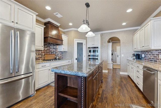 kitchen featuring appliances with stainless steel finishes, dark hardwood / wood-style flooring, premium range hood, a kitchen island, and white cabinetry