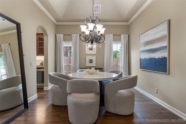 dining space with dark wood-type flooring, crown molding, lofted ceiling, and a notable chandelier