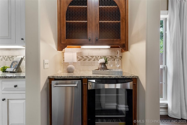 bar featuring decorative backsplash, light stone countertops, and beverage cooler