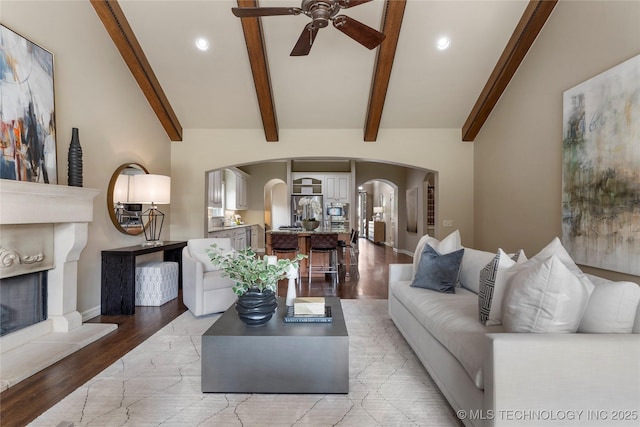 living room with ceiling fan, light hardwood / wood-style flooring, and lofted ceiling with beams